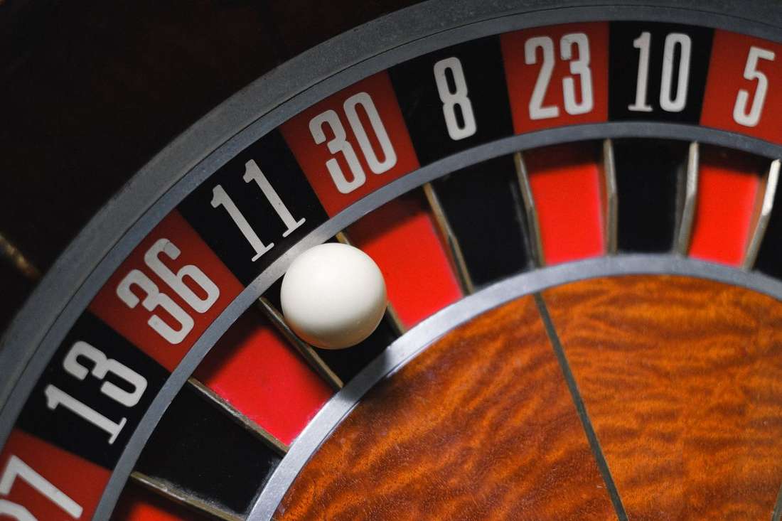 Meja roulette dengan roda berputar dan papan taruhan berwarna